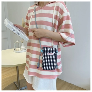 Detail of checkered crossbody phone bag with adjustable rope strap and snap button closure
