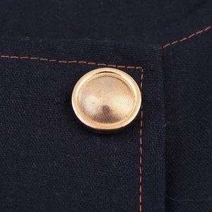 Detail of double-breasted top with gold metal buttons and orange contrast stitching