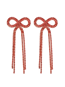 Macro view of long bow tassel earrings featuring sparkling red crystals on a white background