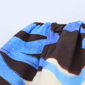 Detail of blue and brown striped fabric featuring waist pleats and floral textures