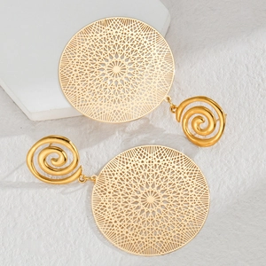 Detailed view of hollow round gold earrings with spiral studs on a white texture background