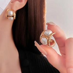 Orecchini vintage a C dorati con trama intrecciata e perle su una modella donna