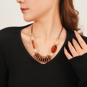 Detail of leather cord necklace with brown and beige resin oval charms on a model