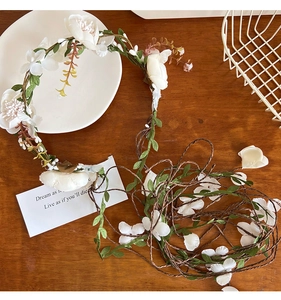 Detailed view of white artificial flower garland with green leaves on brown vine
