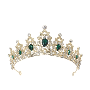 Detailed close-up of golden crown featuring clear rhinestones and green emerald gems