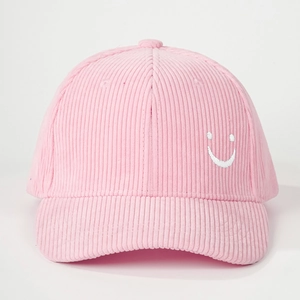Close-up of pink corduroy baseball cap featuring a white embroidered smiley face logo