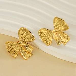 Gros plan détaillé des boucles d'oreilles nœud plaqué or 18K avec texture métal brossé