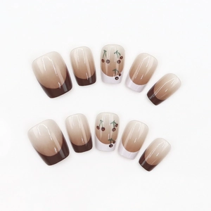 Short square press-on nails with caramel gradient, French tips and cherry art detail