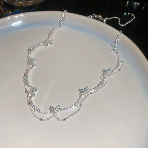 Macro detail of silver necklace featuring blue zircon butterfly charms on wavy chains