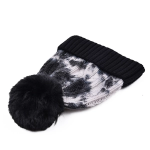 Detailed knit texture of tie-dye winter beanie with a fluffy black faux fur pom pom