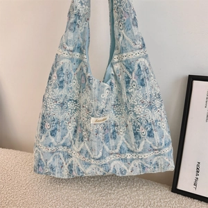 Close-up of light blue lace shoulder bag with intricate white floral embroidery details