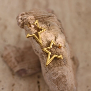 Macro shot of gold star earrings with hammered texture on natural stone base