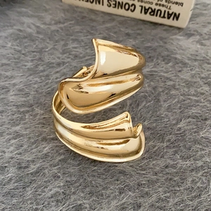 Detail eines unregelmäßig gefalteten goldenen Armreifs mit abstrakter Textur auf Samt