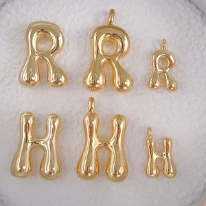 Macro shot of gold bubble alphabet pendants in letters R and H with glossy metallic finish