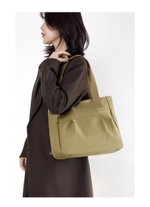 Khaki canvas tote bag shown on shoulder with front pocket and minimalist design