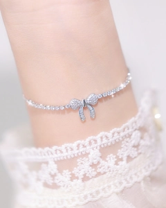 Close-up of sparkling bow pendant tennis bracelet worn with elegant lace sleeves
