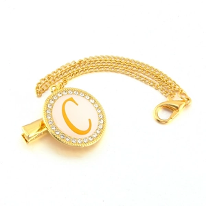 Detailed view of golden pacifier clip with crystal rhinestone letter C on white enamel