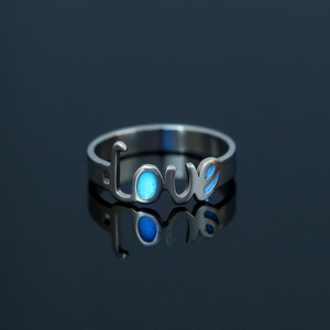 Luminous stainless steel ring with glowing blue LOVE lettering on a reflective surface