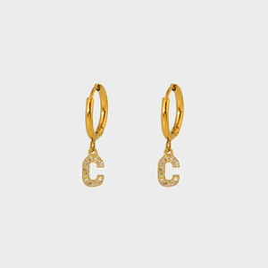 Close-up of gold-plated hoop earrings with sparkling zircon-studded letter C pendants
