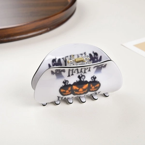Detail of white Happy Halloween hair claw clip featuring festive pumpkin and ghost motifs