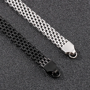 Detail von silbernen und schwarzen Edelstahl-Mesh-Armbändern auf strukturiertem Hintergrund