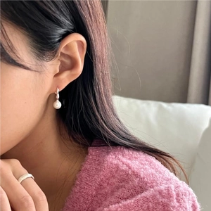 Close-up of S925 sterling silver heart pearl earrings on a model wearing purple sweater