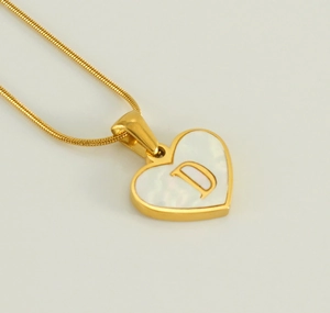 Detailed close-up of 18K gold heart pendant with shell inlay and letter D engraving