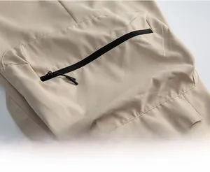 Dettaglio dei pantaloni cargo che mostra il tessuto kaki e la tasca con zip nera
