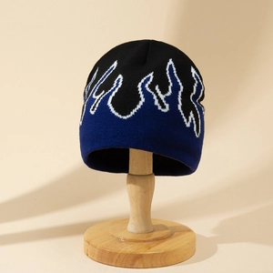 Black and blue flame jacquard knit beanie for winter on a wooden display stand