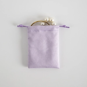 Detail of light purple suede drawstring jewelry pouch with gold ring and pearls