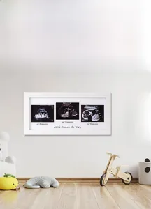 Close-up of white wooden frame for three ultrasound photos with pregnancy trimester text
