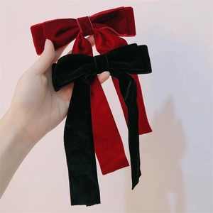 Red and black velvet bow hair clips with long streamers shown on a plain white background