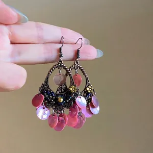 Detail of ethnic boho earrings with bronze metal frame and hanging purple shell tassels