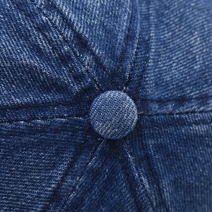 Detailed macro view of navy blue denim baseball cap stitching and top button texture
