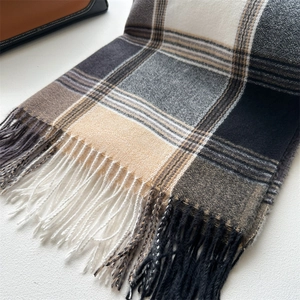 Detail of soft plaid scarf with tassels in black, grey, cream and beige checkered pattern