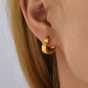 French luxury heart-shaped gold titanium steel hoop earrings on model with polished finish
