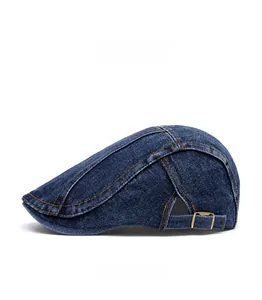Detail of dark blue denim beret featuring orange contrast stitching and adjustable metal buckle