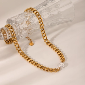 Gold Cuban chain necklace with white baroque pearl pendant on glass bottle display