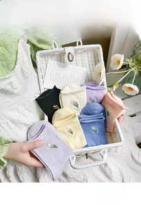 Detail of colorful cotton crew socks with delicate tulip embroidery in a woven basket