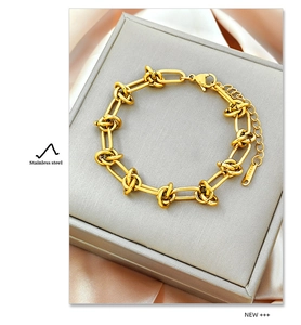 Détail d'un bracelet gourmette doré en acier inoxydable sur un élégant fond en satin