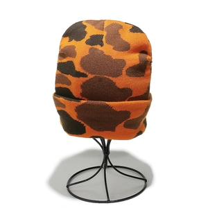 Close-up of thick knit camo beanie with folded cuff in orange and brown tones