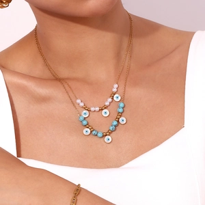 Close-up of double layer gold necklace featuring blue evil eye pendant and white pearls