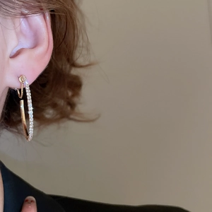 Close-up of gold hoop earrings with sparkling diamonds on a model for a luxury look