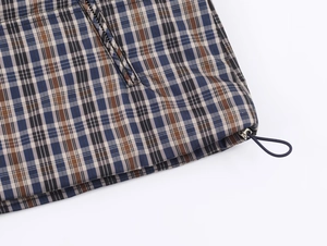 Detail of adjustable elastic drawstring hem on a plaid jacket with navy and brown patterns