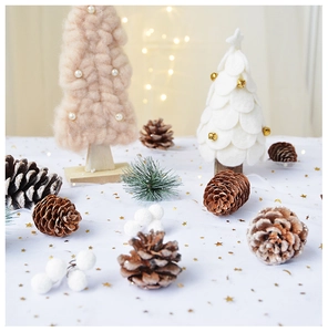 Close-up of knit pearl and felt bell miniature Christmas trees with natural pine cones