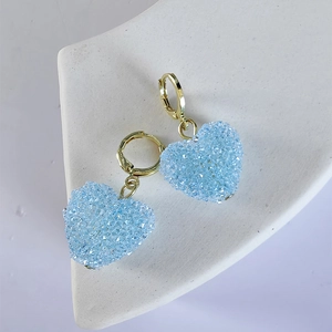 Detail of sweet blue heart drop earrings with glittery texture and golden clasps