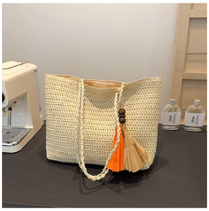 Detail of straw tote bag featuring colorful orange and brown tassels with wooden beads
