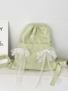 Light green drawstring backpack with floral lace bows and textured canvas fabric