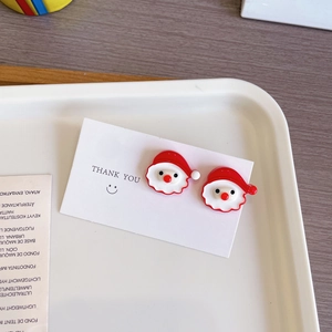 Détail des boucles d'oreilles Père Noël mignonnes sur une carte de présentation festive