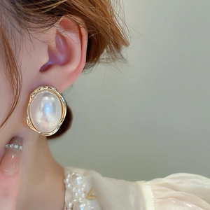 Gros plan de boucles d'oreilles ovales dorées avec perles blanches sur un mannequin